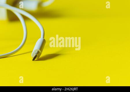 White cable with micro usb plug on a yellow background.  Stock Photo