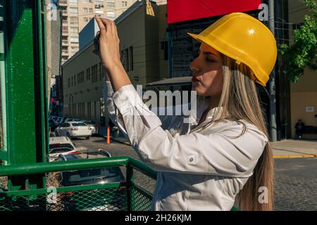 Beautiful young woman engineer or supervisor, taking a photo with her cell phone of the railway bridge she is inspecting. Concept of empowered woman, Stock Photo