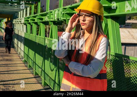 Beautiful young engineer or supervisor, wearing safety gear, talking on cell phone. concept of empowered woman, professional woman, professional job, Stock Photo