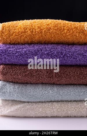 multicolored towels folded, on white table and black background. Stock Photo