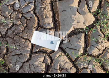 Ukraine. Donetsk region. August 2021. iPhone SE rests on cracked dry textured ground. Stock Photo