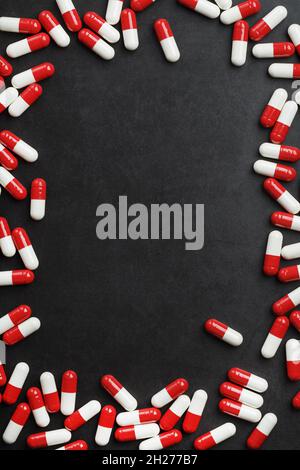 Red and white tablets in the form of a frame with free space on a black background. Ampoule frame, top view Stock Photo