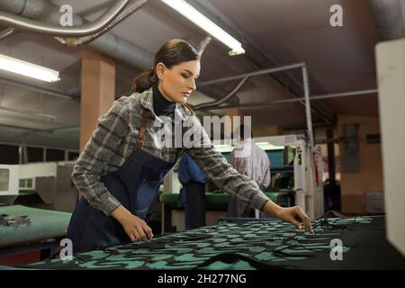 Female worker using special cutting machine in workshop of shoe manufacturing factory Stock Photo