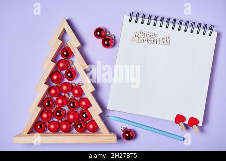Christmas composition of open blank notepad and Wooden christmas tree with red christmas balls inside on pink paper background Stock Photo