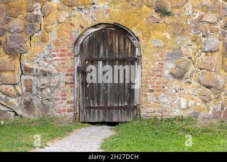 Old dark brown wooden door with arch in a stone wall, background photo texture Stock Photo