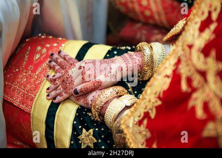 Close up hands and nails of Asian Muslim bride with henna paint tattoo and jewelry in a wedding ceremony. Traditional Minangkabau culture heritage.