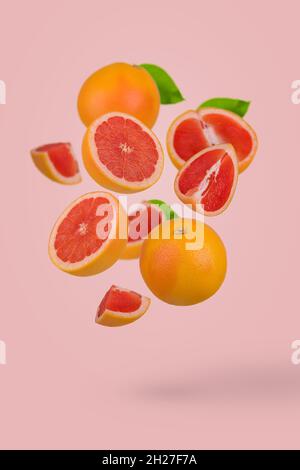 Fresh grapefruit sliced on pastel pink background. Minimal fruit concept. Vitamins, healthy diet concept. Sliced and whole grapefruit floating in the Stock Photo