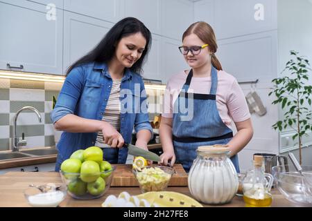 Mom and teenage daughter preparing apple pie together Stock Photo