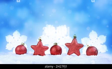 Beautiful Christmas red balls and stars on snow. Red Xmas baubles. Holiday concept. Stock Photo