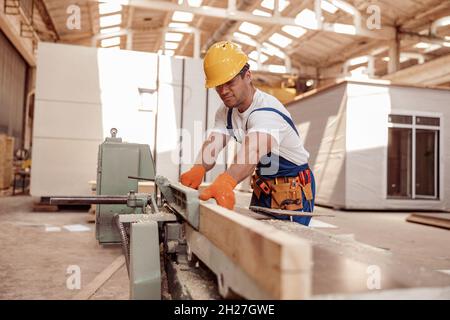 Handsome young man using woodworking machine in workshop Stock Photo