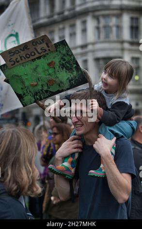 London, UK. 19th Oct, 2021. A child on her father's shoulders holds a sign that says Save Our Schools during the demonstration.Representatives from maintained nursery schools and supporters gathered in Parliament Square, London before delivering a petition to the Chancellor in Downing Street, calling on him to take urgent action and provide adequate funding for them as part of the government's leveling up agenda. Credit: SOPA Images Limited/Alamy Live News Stock Photo