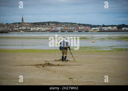 caucasian man using a metal detector on the beach on brittany Stock Photo