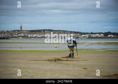 caucasian man using a metal detector on the beach on brittany Stock Photo