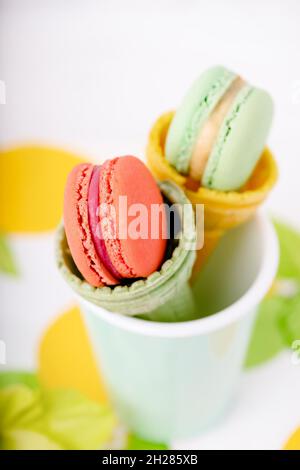 Wafer cup for ice cream with macarons and green gladiolus on a light background Stock Photo