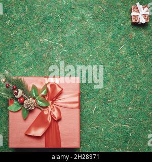 Two red gift boxes of different sizes stand in opposite corners against a background of green moss. Top view Stock Photo