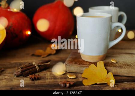 Pumpkin spiced coffee in ceramic cups on a wooden table with orange pumpkins in the background. Bokeh. Autumn mood. Time to drink hot beverage. Stock Photo