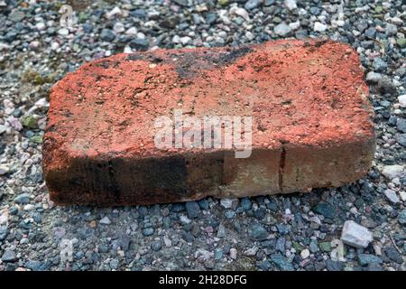 Close-up of an old rweathered red brick lying on the ground. Stock Photo