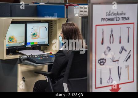 Bangkok, Thailand. 20th Oct, 2021. Airport security officer wearing a face mask as preventive measure seen X-ray baggage scanning at Don Muang International Airport during the Coronavirus crisis.Thailand's government set to reopen the country on November 1, 2021, enabling fully vaccinated international tourists from at least ten low-risk countries to enter the country without having to go through quarantine. The reopening is intended to promote the tourism industry as well as the economy of the country. (Photo by Peerapon Boonyakiat/SOPA Images/Sipa USA) Credit: Sipa USA/Alamy Live News Stock Photo