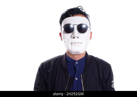 Man with white mask, wearing black glasses. Isolated on white background. Costume concept. young man taking off plain white mask revealing face Stock Photo