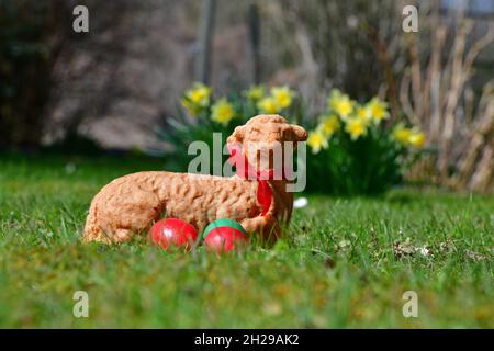 Ostereier und ein gebackenes Osterlamm in einer Wiese mit gelben Blumen im Hintergrund - Easter eggs and a baked Easter lamb in a meadow with flowers Stock Photo