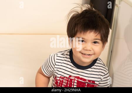2 of 2 Two year old boy showing his face smiling after hiding behind his hands peek a boo Stock Photo