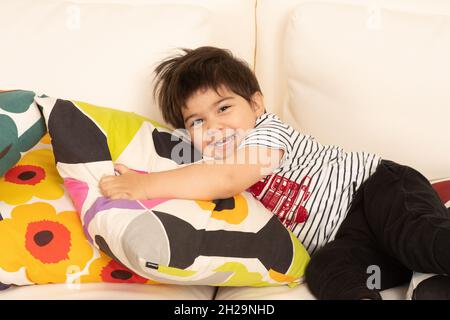 2 of 2 Two year old boy showing himself after hiding behind cushion hide and seek peek a boo Stock Photo