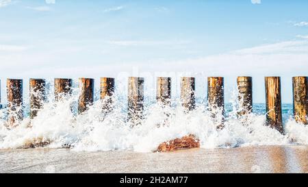 Waves crashing on a wooden breakwater against the background of the sea, the sea horizon and the sky Stock Photo