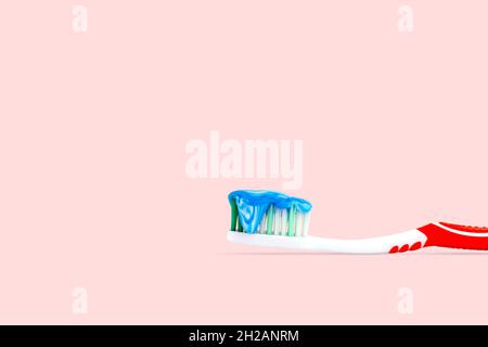 Closeup a blue and white toothpaste on a toothbrush isolated on pink color background. Stock Photo