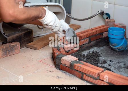 Construction workers are laying red bricks around the sewer in the bathroom. Stock Photo