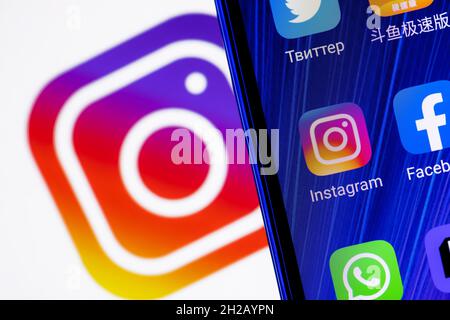 The icon of the Instagram social network application among other applications on the smartphone screen. On the background is the Instagram logo. Stock Photo