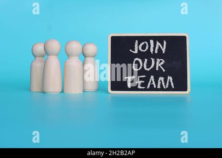 Recruitment and hiring concept. Wooden dolls and mini blackboard with text JOIN OUR TEAM on blue background Stock Photo