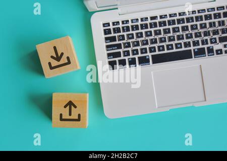Internet and technology concept. Top view of laptop and wooden blocks with upload and download icon logo. Stock Photo