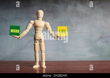 Work life balance concept. Wooden human figure balancing two wooden blocks with text WORK and LIFE Stock Photo