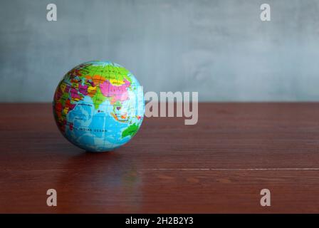 Earth globe on wooden table against concrete wall. Copy space for text Stock Photo