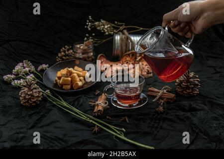 Bael fruit tea  is poured from a kettle into glass cup with bark of bael fruit, brown cane sugar cube Crispy butter toast. The properties of hot bael Stock Photo