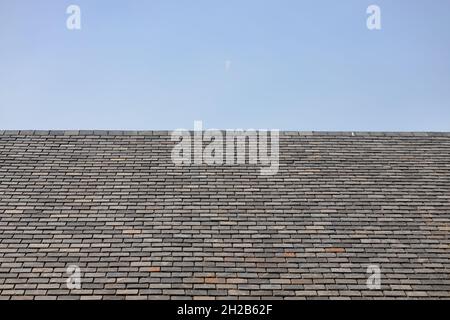 Slate roof against blue sky. Background, abstract, pattern, construction, architecture, sustainability concept. Stock Photo