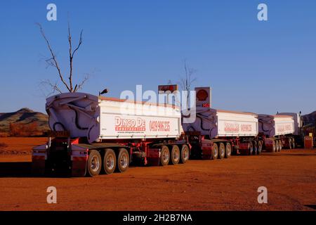 Road train and red earth soon before sunset at Auski Roadhouse and tourist village in outback near Karijini National Park, Pilbara, Western Australia Stock Photo