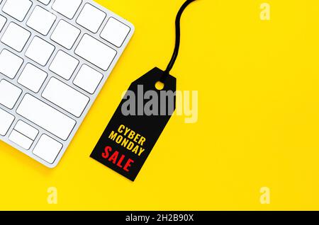 Black price tag with wireless keyboard for online shopping on yellow background. Cyber Monday concept. Stock Photo