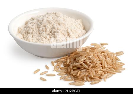 Brown rice flour in a white ceramic bowl next to a pile of brown rice isolated on white. Stock Photo