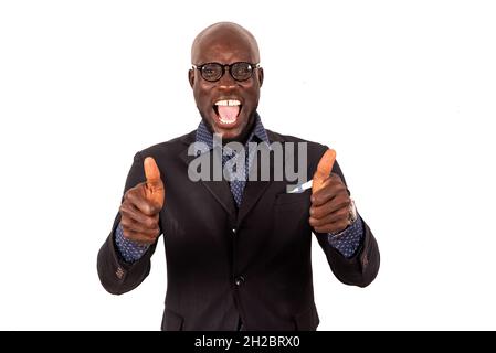 Handsome young businessman in suit standing on white background gesturing with thumbs and looking at the camera shouting with joy. Stock Photo