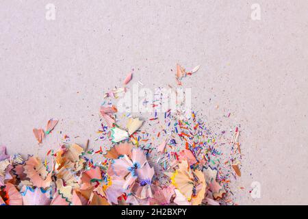 Wooden pencil shavings and colorful crumbs of graphite from sharpener on soft pink pastel paper background. Top view. Design elements for poster, bann Stock Photo