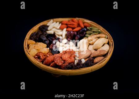 Group of various types of dried fruits and dried on a bamboo tray on black background. Stock Photo