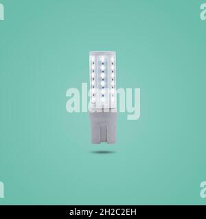 LED energy saving lamp 230v in a ceramic socket isolated on green pastel color background. Stock Photo