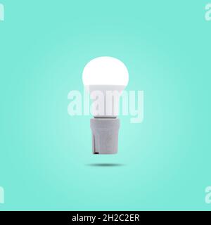 LED energy saving lamp 230v in a ceramic socket isolated on green pastel color background. Stock Photo