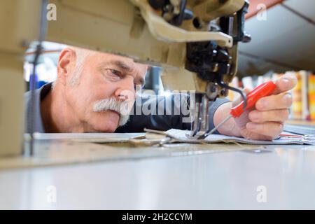close view of senior man repairing sewing machine with screwdriver Stock Photo