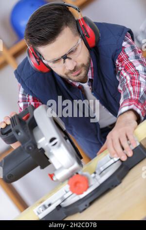 carpenter cutting flaxboard using sliding compound mitre saw Stock Photo