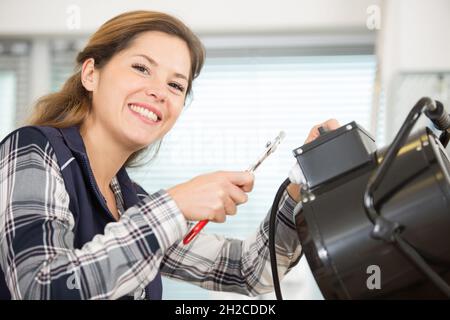 female electrician posing while working on appliance Stock Photo