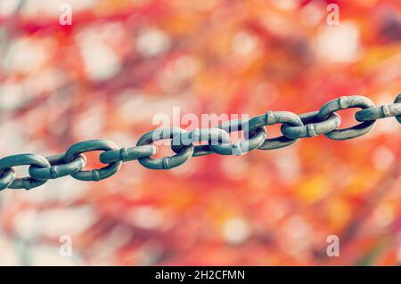 Close up view of rusty metal chain links on a blurred multicolored background. Stock Photo