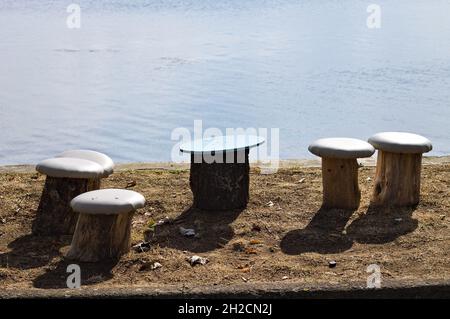 Mushroom-shaped seats made from wood logs along the shore of Lake Trasimeno (Umbria, Italy, Europe) Stock Photo