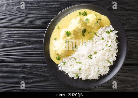 Traditional recipe for Danish Meatballs in Curry Boller i Karry with rice garnish close up in the plate on the table. horizontal top view from above Stock Photo